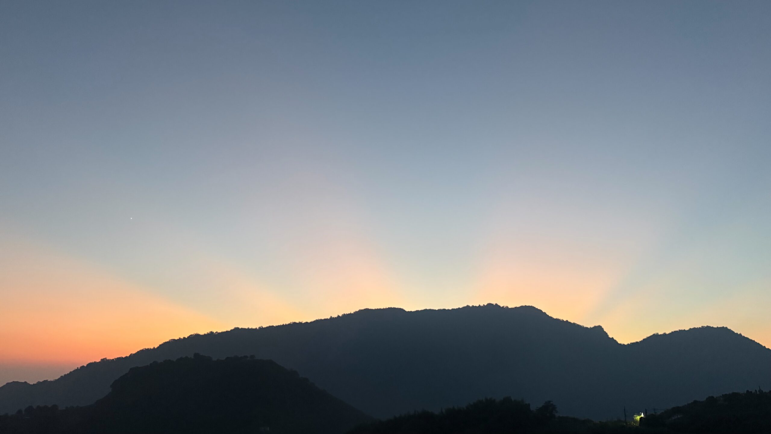 楓怡竹石望向摩天嶺層疊山景，橙色天光映襯深色山稜